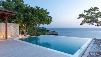 Obraz premium Luxurious infinity pool overlooking serene ocean at sunset, surrounded by lush greenery