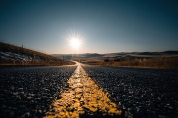 A captivating low-angle shot of a highway stretching into the horizon, bathed in the warm glow of the morning sun, with rolling hills and clear blue sky, creating a sense of adventure.