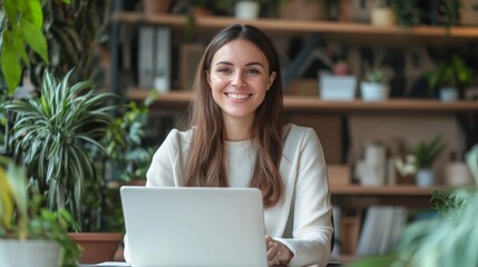 Smiling woman working on laptop in a cozy indoor garden filled with plants during daylight
