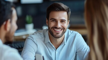 Obraz premium Smiling man engages in friendly conversation with colleagues in a modern office setting during daytime