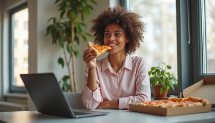 A cheerful young woman with curly hair takes a bite of delicious pizza, radiating happiness in a bright, modern workspace. The scene captures a perfect blend of productivity and indulgence, showcasing