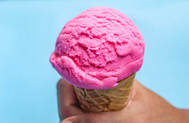 hand holding strawberry ice cream on blue background