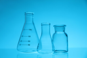 Empty flasks on light blue background. Laboratory equipment