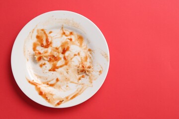Dirty plate on red background, top view. Space for text