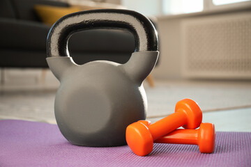 Fototapeta premium Kettlebell and dumbbells on fitness mat at home