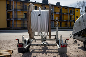 Huge industrial wooden cable spool with coiled white cable on a mobile trailer