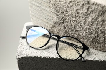 Stylish glasses on stone surface against light grey background, closeup