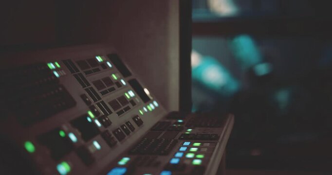 A detailed control panel is illuminated with various green and blue buttons, set within a darkened space station environment. The atmosphere is high tech and futuristic.