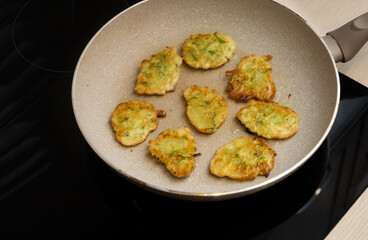 zucchini pancakes on a frying pan on an induction cooker