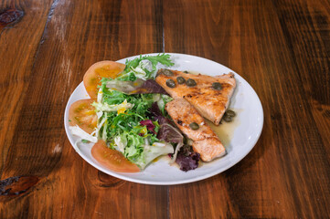 A plate of food with a piece of chicken and a salad