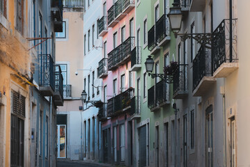 A narrow backstreet in Bairro Alto, Lisbon, is lined with pastel-coloured buildings, capturing the historic charm and quaint atmosphere of this Portuguese neighbourhood on a quiet summer day.