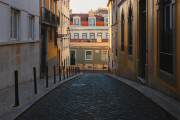 A narrow, cobblestone alley in Bairro Alto Lisbon, glows in the golden hour light, capturing the...