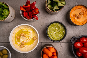 Various hummus dips. Hummus plate with vegetable snacks. Carrot, cucumber, tomato, celery sticks,...
