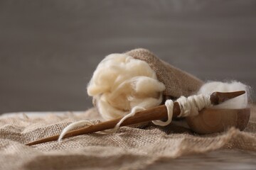 Soft white wool and spindle on table. Space for text