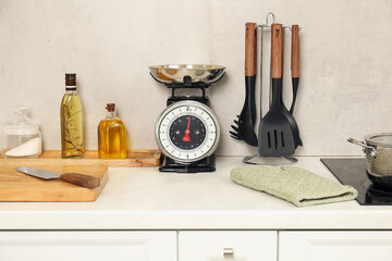 Retro mechanical kitchen scale and other utensils on white marble countertop indoors