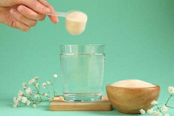 Woman adding collagen powder into glass with water on turquoise background, closeup