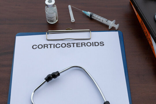 A clipboard holds a corticosteroids medical document beside a stethoscope on a warm wooden desk, reflecting a professional healthcare environment.