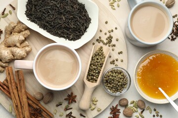 Aromatic Masala tea in cups, spices, dry leaves and honey on light grey table, flat lay