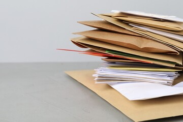Post office. Stack of different paper envelopes on grey table, closeup. Space for text