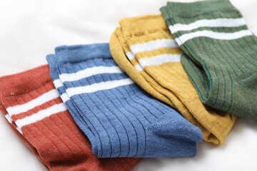 Different soft socks on white blanket, closeup