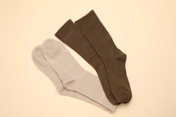 Pairs of stylish socks on beige background, top view