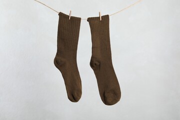Pair of socks hanging on washing line against light grey background