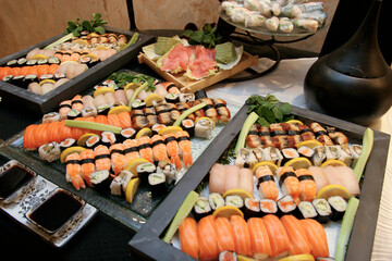 Display of assorted sushi rolls and sashimi on platters at a buffet