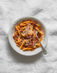 Quick and simple pasta with bacon and canned beans in tomato sauce on a light background, top view
