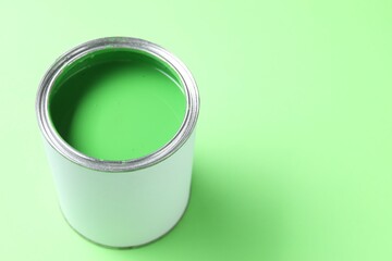 Can of bright paint on light green background, closeup. Space for text