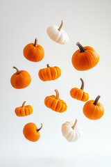 Small orange and white pumpkins floating in the air on a white background