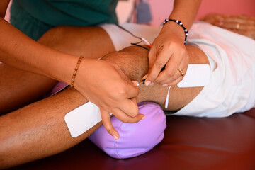 Doctor, therapist applying electrodes on patients knee for tens therapy