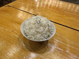 A steaming bowl of perfectly cooked white rice, sprinkled with contrasting black sesame seeds