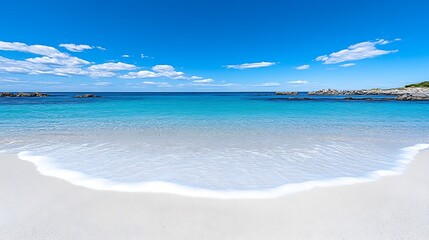 Obraz premium Gentle Waves Lapping at Secluded Beach Under Bright Blue Sky with White Clouds