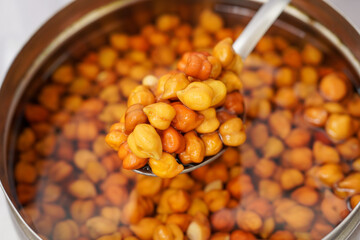 Soaked chickpeas (also known as kala chana) textured background, chick pea in water closeup, swollen wet Cicer arietinum fruits, macro raw Bengal gram legume preparation.