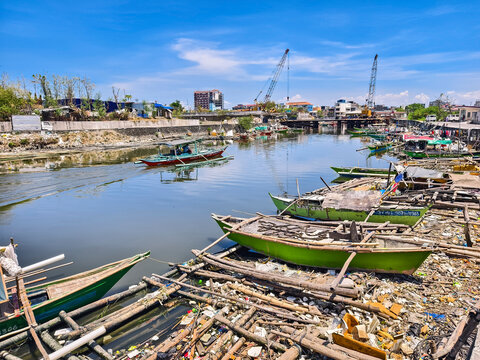 Las Pinas, Metro Manila - April 12, 2025: Small fishing boats float along the trash-filled Zapote River, reflecting urban poverty and pollution.