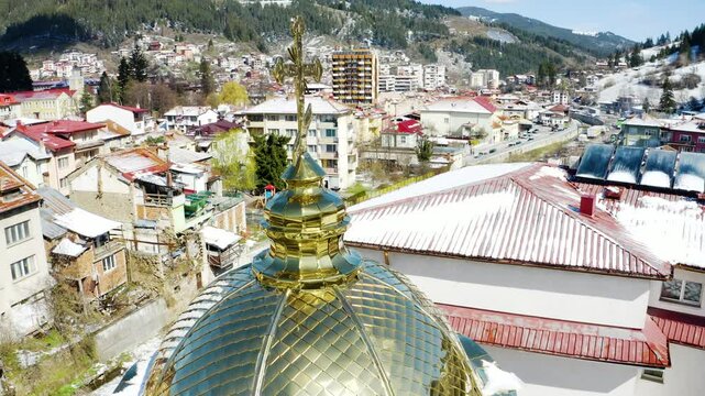 Drone footage of a beautiful shiny golden cross on top of a church