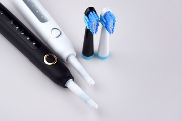 Modern electric ultrasonic toothbrush with rechargeable battery on a gray surface.