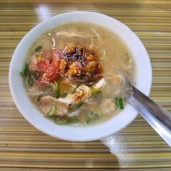 A bowl of flavorful chicken soup with noodles and toppings.