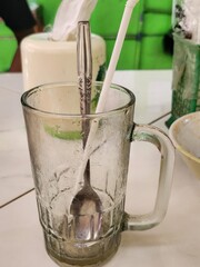 An empty iced beverage glass with a spoon and straw.