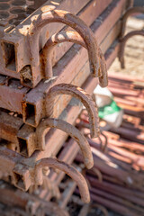 This close-up photograph captures a detailed view of a stack of rusted industrial metal frames with curved hooks.The weathered surfaces, oxidation, textures highlight the effects of prolonged exposure