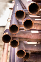 This close-up photograph captures the ends of several rusty metal pipes stacked together at a...