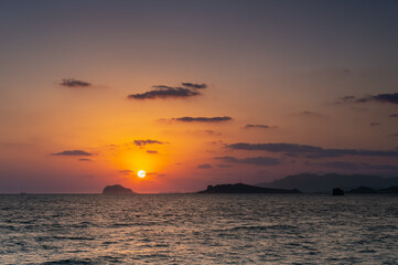 A stunning spring sunrise in Jinshan, New Taipei, Taiwan. The sun rises over Keelung Islet, casting a warm glow across the ocean with islands in silhouette.