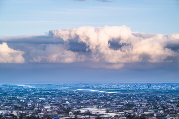 A tranquil spring afternoon in Yilan, Taiwan, showcases the city skyline stretching toward the sea, with Turtle Island silhouetted against the sky.