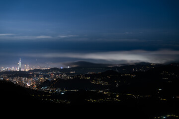 A poetic spring night at Lion's Head Mountain in Taiwan. The city breathes softly as clouds dance in harmony over the glittering skyline, weaving dreams of tranquility and wonder.