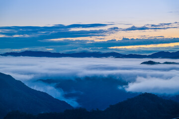 A serene spring dawn at Lion Head Mountain, Taiwan. Orange skies meet flowing white clouds, with silhouettes of power line towers.