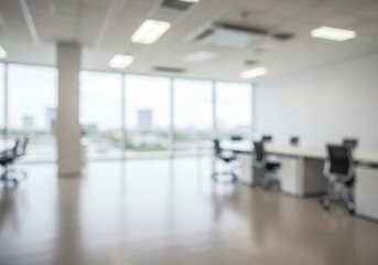 Fototapeta premium Blurred view of a modern office space with desks chairs and large windows letting in natural light