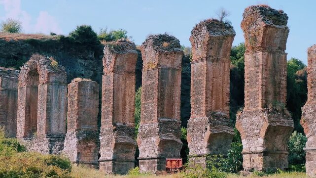 The ancient city of Aspendos. Ruins of aqueducts of Aspendos Acropolis. T&uuml;rkiye. Historical siphon of Aspendos Aqueduct with olive trees, Antalya. 4K