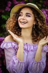 Beautiful girl in straw hat in lilac Garden. Girl with lilac flowers in springtime. Gardening 