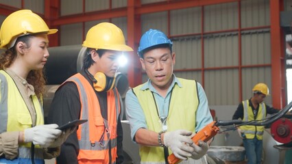 Supervisor senior man training controlling overhead crane with remote new worker in manufacturing, Engineering team use remote control panel for lifting down power trolley crane in factory warehouse