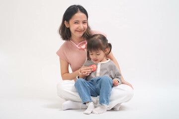 A joyful mother and her adorable child sitting together in a studio setting, sharing a tender moment of playfulness and love.